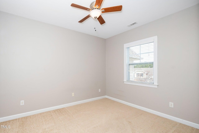 empty room featuring a ceiling fan, light carpet, visible vents, and baseboards