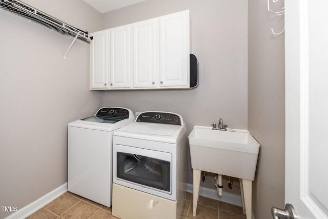 laundry area featuring light tile patterned floors, a sink, washing machine and dryer, and cabinet space