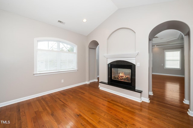 unfurnished living room featuring wood-type flooring, visible vents, vaulted ceiling, and a multi sided fireplace