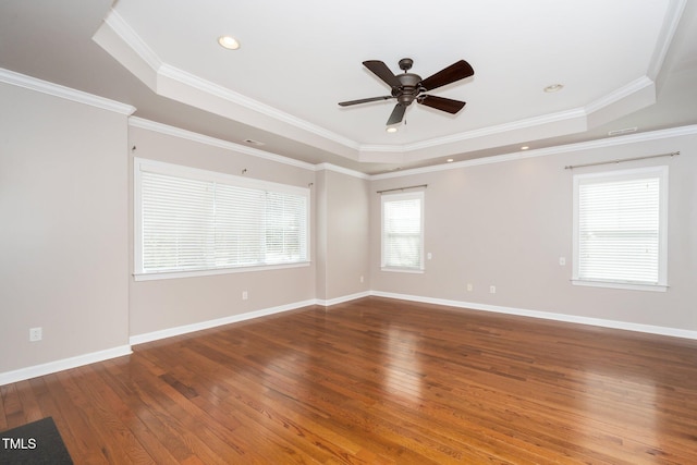 empty room with hardwood / wood-style floors, a raised ceiling, and baseboards