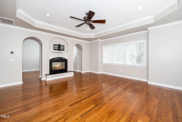 unfurnished living room featuring a tray ceiling, visible vents, arched walkways, and a multi sided fireplace