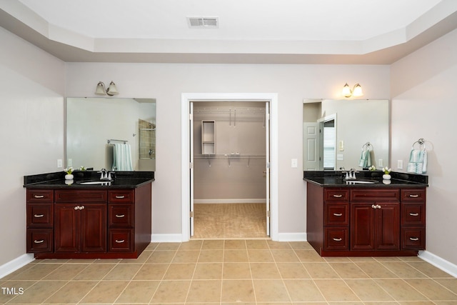 full bathroom with visible vents, two vanities, tile patterned floors, a shower stall, and a sink