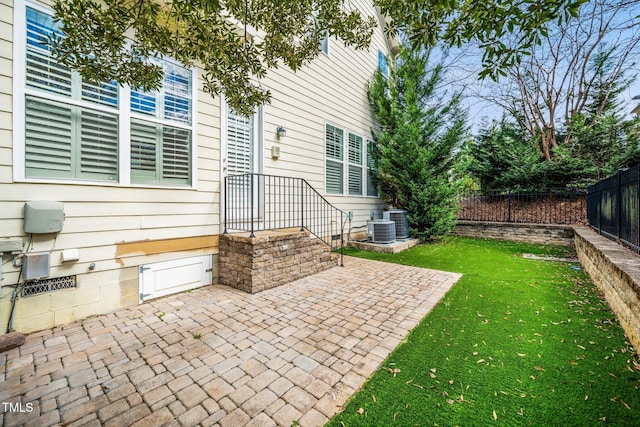 exterior space with central air condition unit, a patio area, fence, and a lawn