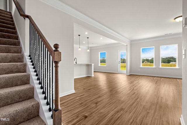 unfurnished living room featuring a wealth of natural light, crown molding, and wood finished floors