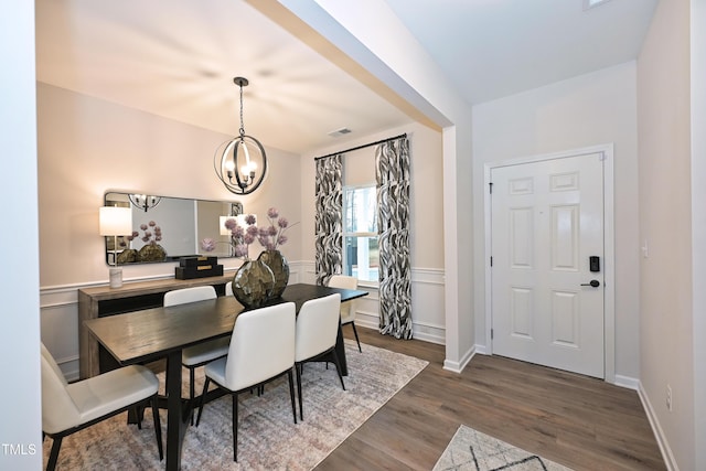 dining room featuring wood finished floors, visible vents, a wainscoted wall, and an inviting chandelier