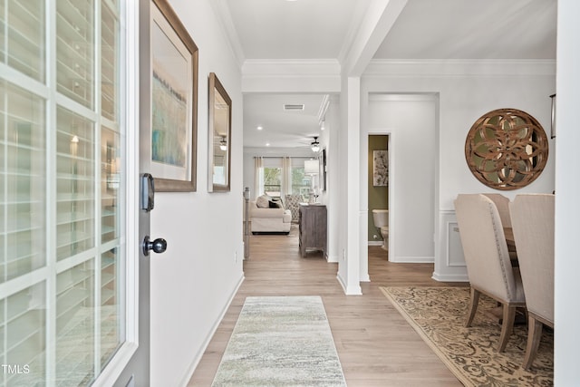 entryway with light wood-style flooring, a ceiling fan, baseboards, visible vents, and crown molding