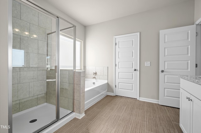 bathroom with a shower stall, baseboards, a bath, and vanity