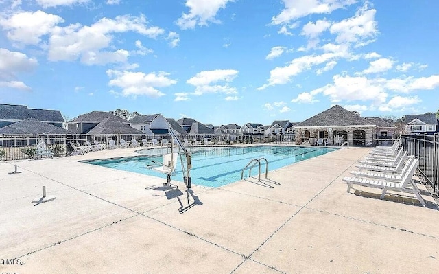 community pool featuring a patio, fence, and a residential view