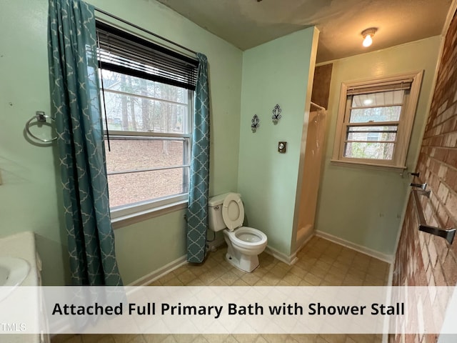 bathroom featuring a wealth of natural light, toilet, and a shower with curtain