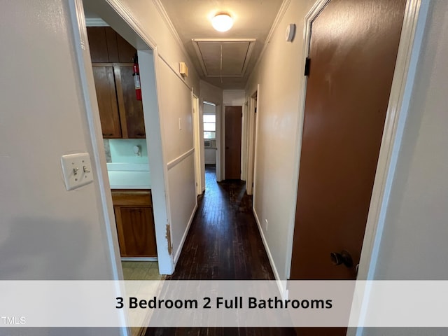 hallway featuring attic access, baseboards, and wood finished floors