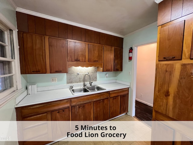 kitchen featuring brown cabinets, ornamental molding, a sink, tasteful backsplash, and light countertops