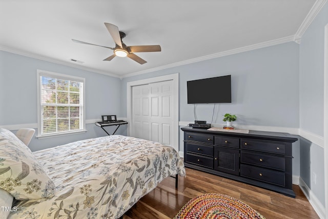 bedroom featuring a closet, visible vents, wood finished floors, and crown molding