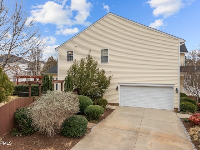 view of property exterior featuring a garage, concrete driveway, and fence