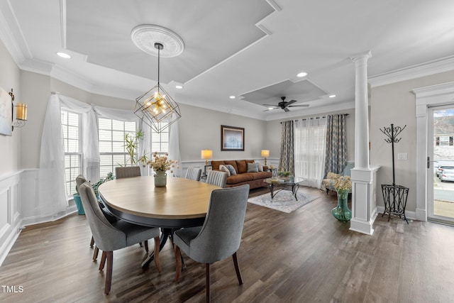 dining area with wainscoting, wood finished floors, crown molding, and ornate columns