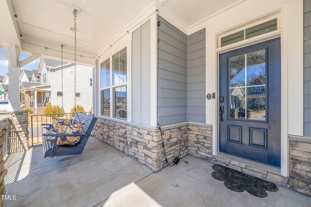 view of exterior entry with a porch and stone siding