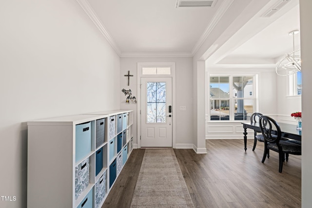 foyer entrance with visible vents, ornamental molding, dark wood-style flooring, and a wealth of natural light