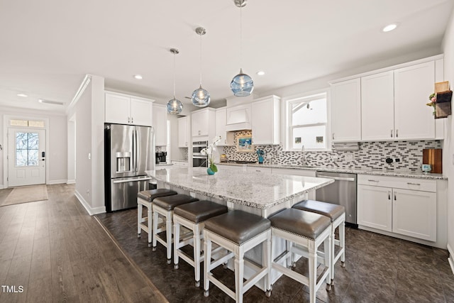 kitchen featuring tasteful backsplash, a kitchen island, a kitchen breakfast bar, stainless steel appliances, and white cabinetry