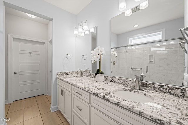 bathroom with double vanity, a stall shower, tile patterned flooring, and a sink