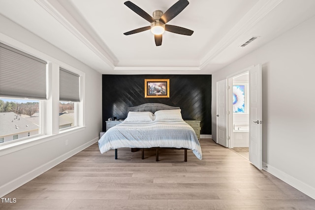 bedroom with an accent wall, a tray ceiling, and multiple windows