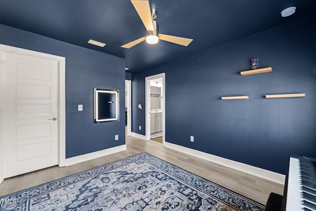 bedroom with ceiling fan, connected bathroom, baseboards, and wood finished floors