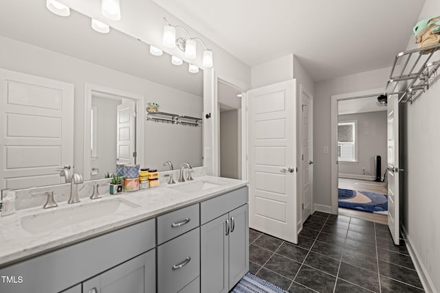 full bathroom featuring double vanity, tile patterned flooring, a sink, and baseboards