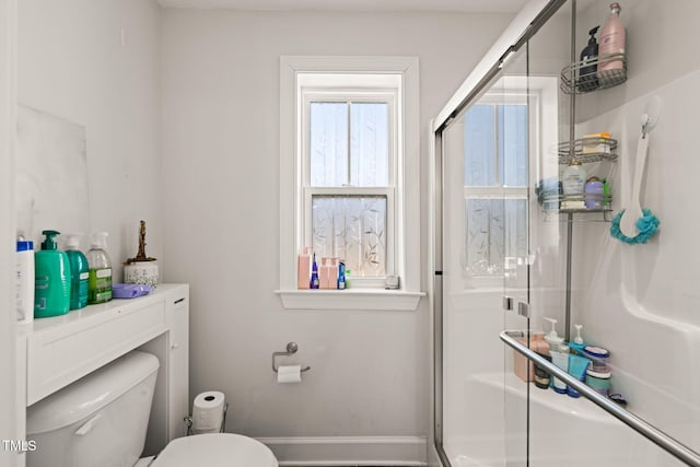 bathroom with an enclosed shower, toilet, and baseboards