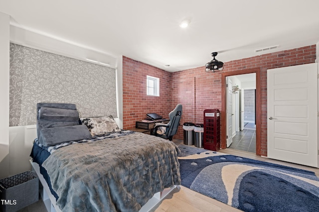 bedroom featuring visible vents and brick wall