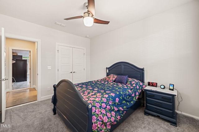 bedroom with carpet floors, a closet, visible vents, black refrigerator, and baseboards