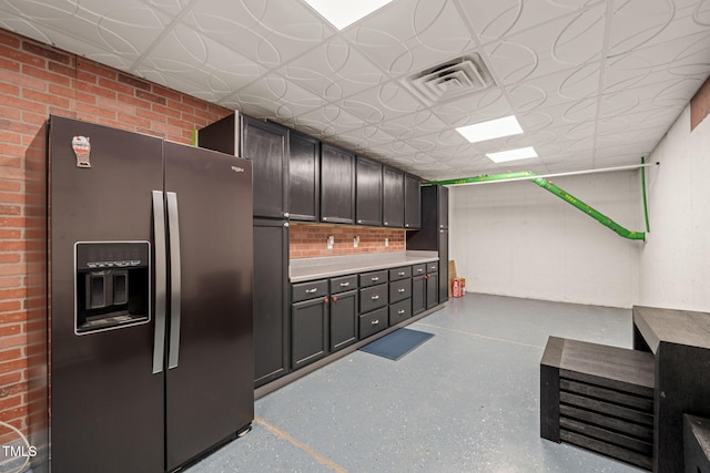 kitchen featuring an ornate ceiling, light countertops, visible vents, fridge with ice dispenser, and brick wall