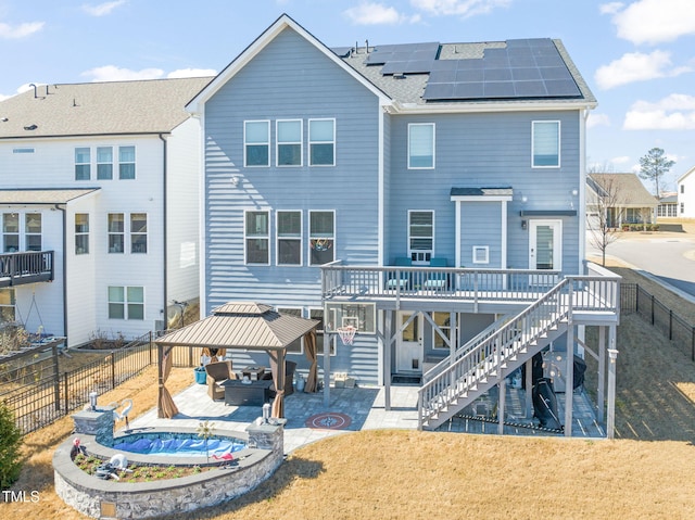 rear view of house featuring a fenced backyard, stairway, a gazebo, a patio area, and roof mounted solar panels