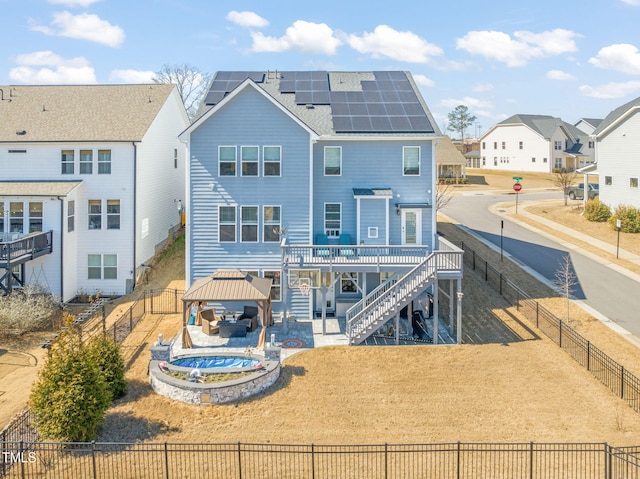 rear view of property with a deck, a fenced backyard, solar panels, a gazebo, and stairway