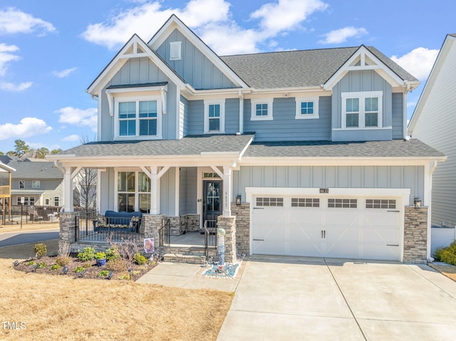 craftsman inspired home featuring driveway, covered porch, board and batten siding, and roof with shingles