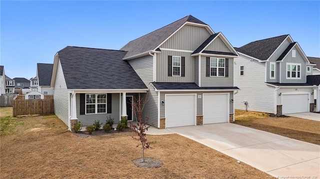 craftsman-style home with a shingled roof, concrete driveway, an attached garage, board and batten siding, and fence