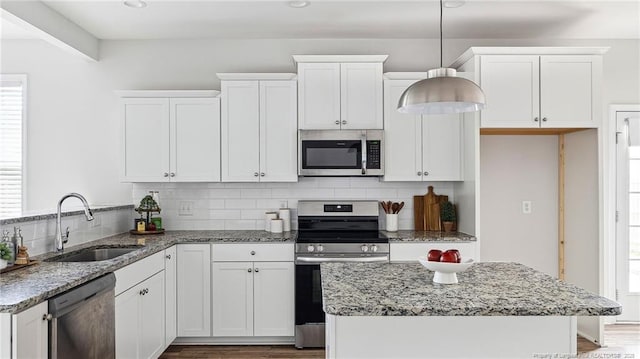 kitchen featuring stainless steel appliances, tasteful backsplash, a sink, and light stone counters