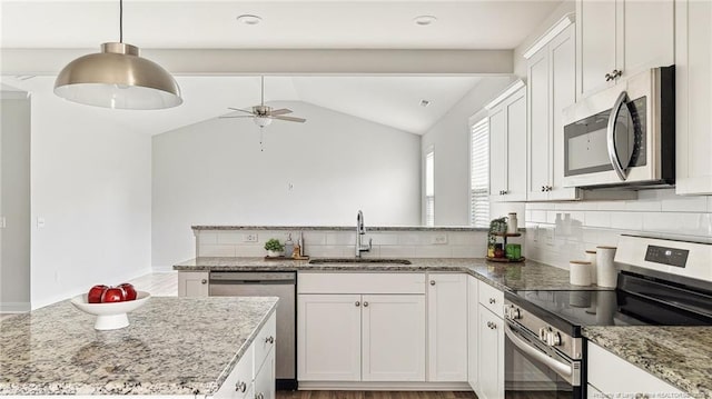 kitchen featuring lofted ceiling, stainless steel appliances, a peninsula, a sink, and tasteful backsplash