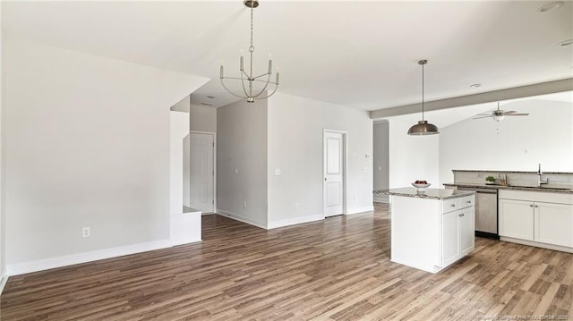 kitchen with stainless steel dishwasher, open floor plan, white cabinets, a sink, and wood finished floors