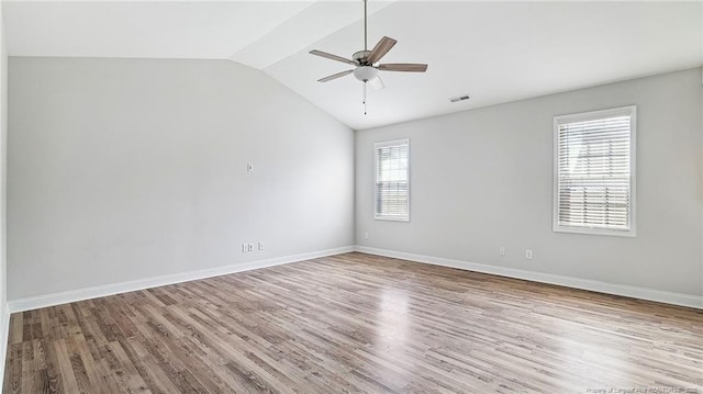 empty room featuring a ceiling fan, lofted ceiling, visible vents, and wood finished floors