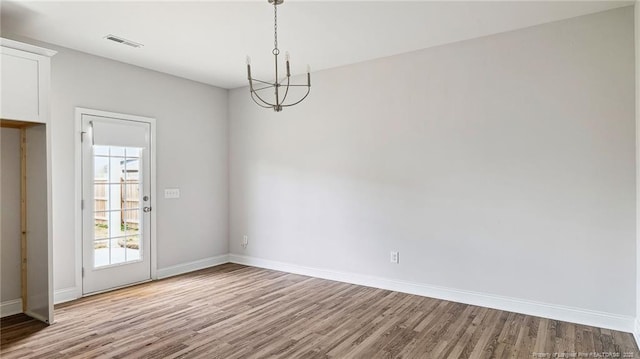 unfurnished dining area with wood finished floors, visible vents, and baseboards