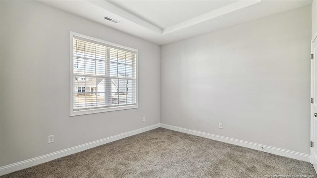 carpeted spare room featuring visible vents and baseboards