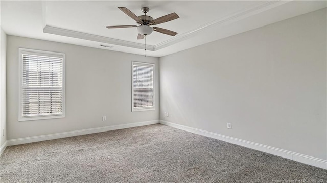 carpeted spare room featuring ceiling fan, visible vents, a raised ceiling, and baseboards