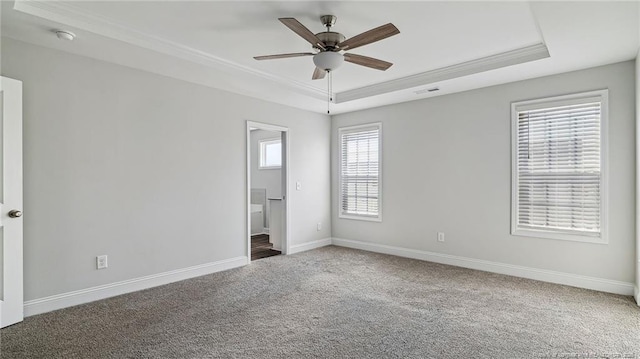 unfurnished bedroom featuring carpet, a tray ceiling, and baseboards