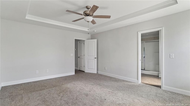 unfurnished bedroom with baseboards, a raised ceiling, and carpet flooring