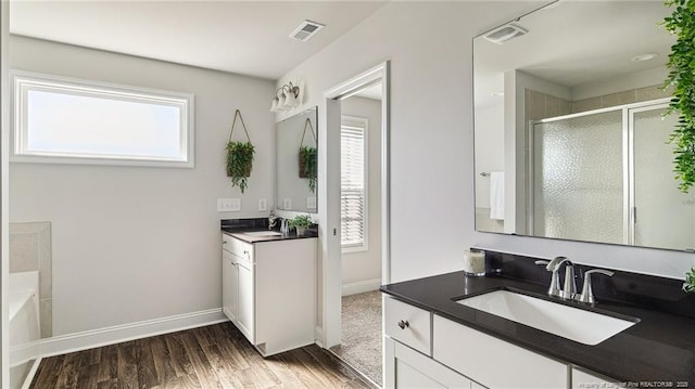 full bathroom featuring wood finished floors, a sink, visible vents, and a shower stall