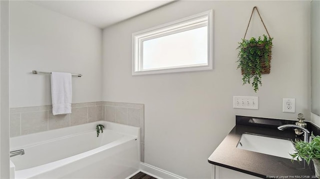 bathroom featuring vanity, baseboards, and a bath