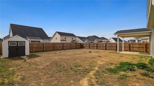 view of yard with an outbuilding, a fenced backyard, a residential view, and a storage shed