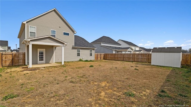 back of property with a patio, a fenced backyard, an outdoor structure, a yard, and a storage unit