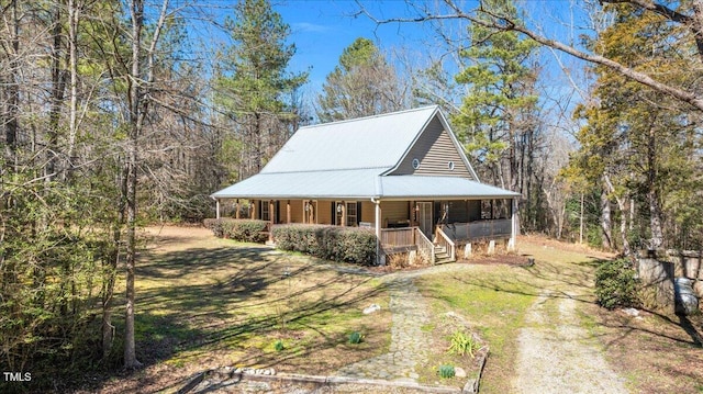 view of front of property featuring covered porch, metal roof, and a front lawn