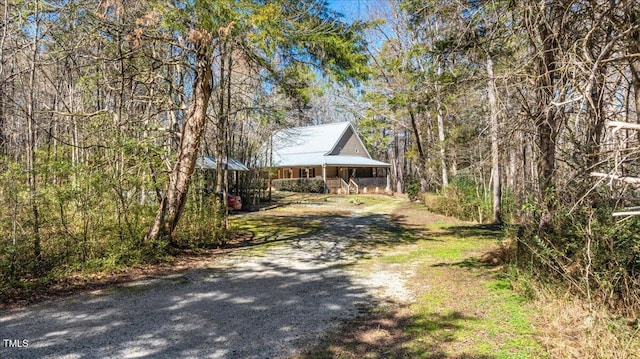 view of front of property with a porch, driveway, and a wooded view