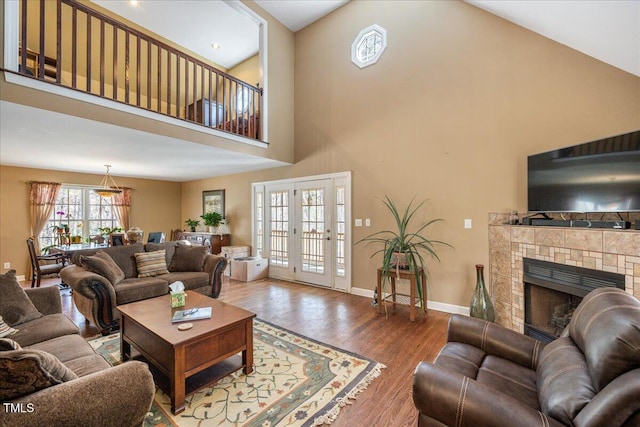 living room with a high ceiling, a fireplace, baseboards, and wood finished floors