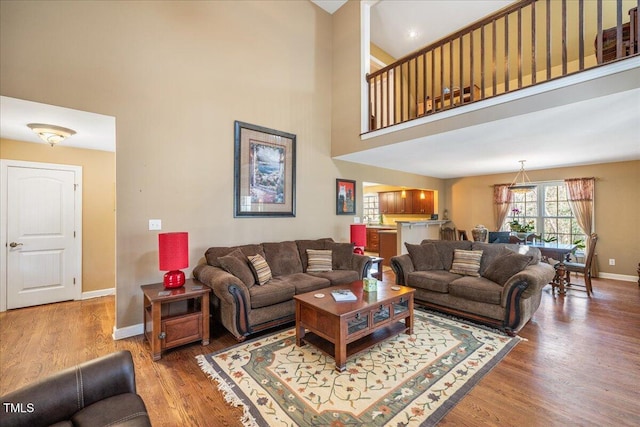 living area featuring a high ceiling, wood finished floors, and baseboards